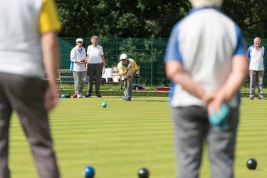 A group of elderly people playing bowls.