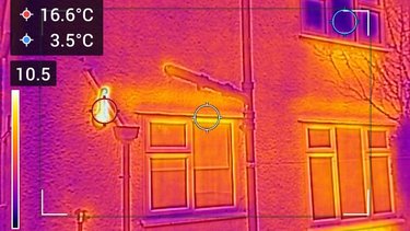 A thermal camera image of a house window, showing how heat escapes from around the window.