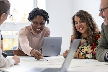 A group of people sit around a table having a meeting.