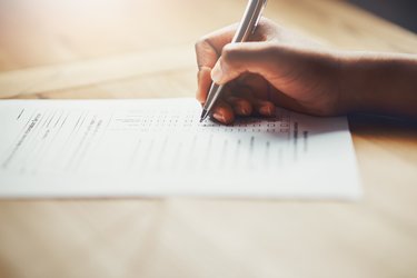 A hand writing on a paper form