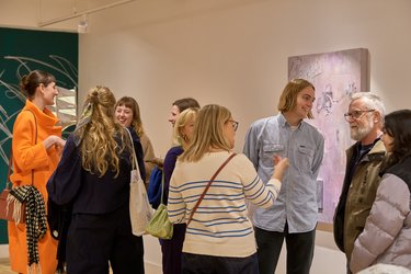 A group of people have a discussion and admire art at a Broadway Gallery exhibition.