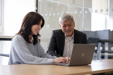 Two people work together on a laptop