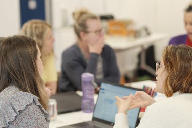 A group of teachers sit around a table, discussing.